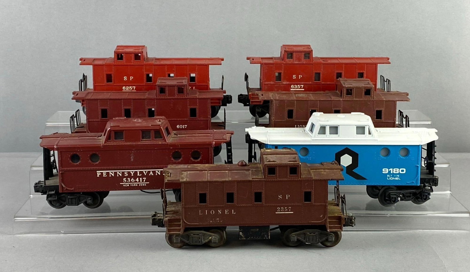 Group of 7 Lionel Trains O Gauge Cabooses: Includes SP line, The Rock Line and more. Some have lighted interior. Untested. Largest measures H 3 x W 2 1/2 x L 8 inches. Stand not included.