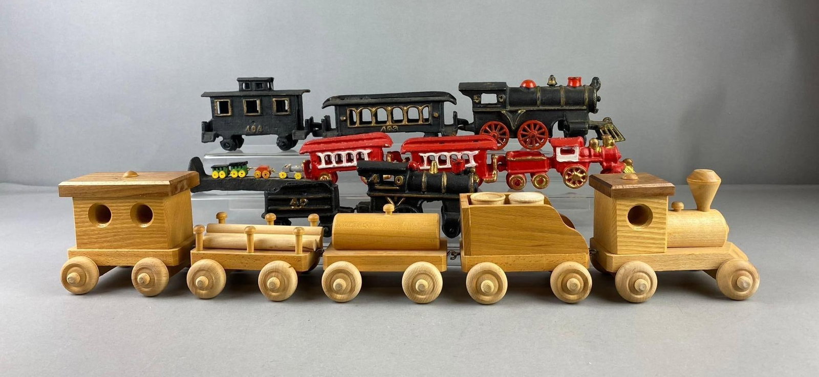 Group of Assorted Cast Iron Train Sets and More: Includes wooden toy train, railroad spike, and more. Largest measures 4? in length. Stand not included.
