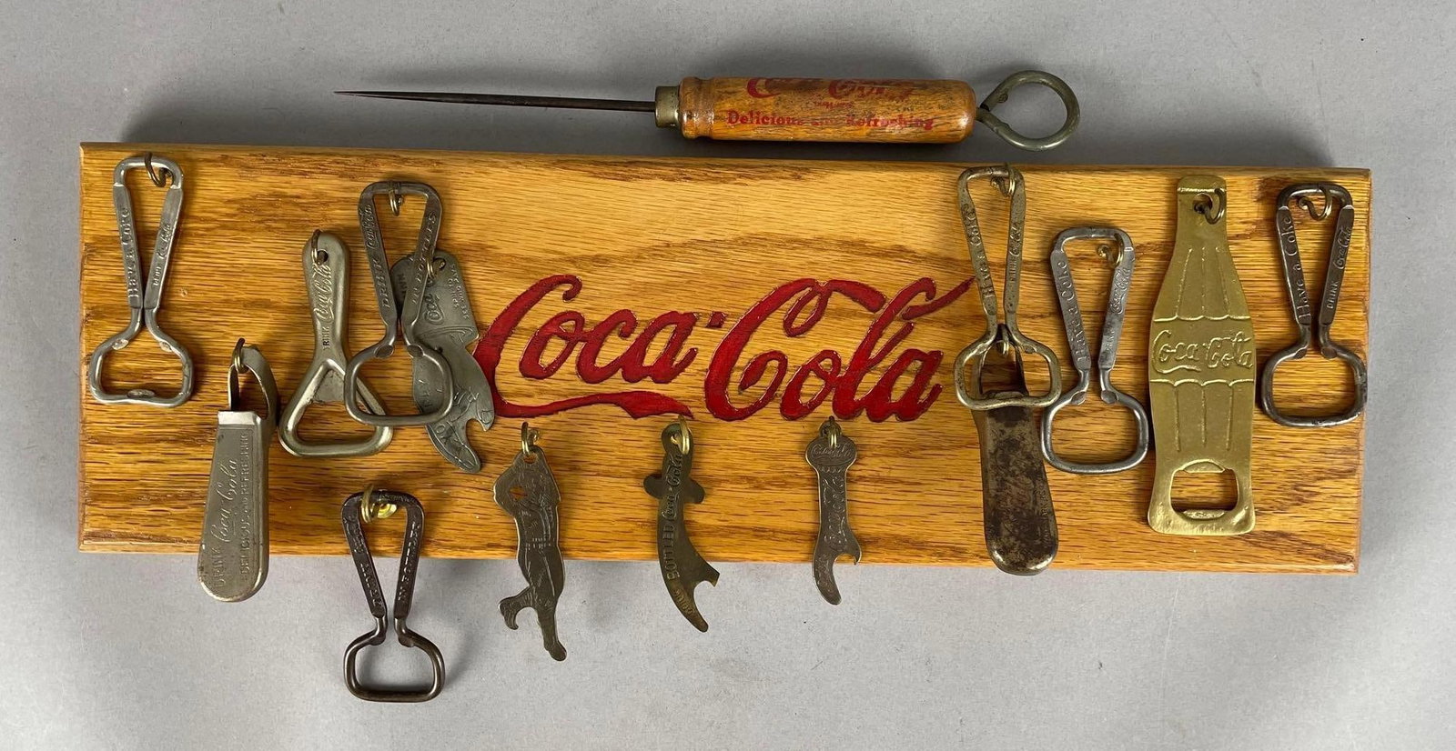 Display of Vintage Coca-Cola Metal Advertising Bottle Openers: Includes ice pick, board measures 6 inches x 18 1/4 inches