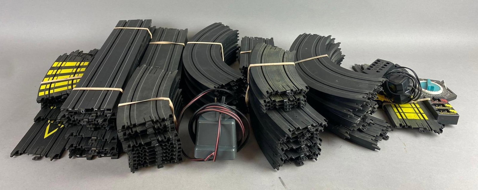 Group of 50+ Tyco Slot Car Tracks and More: Includes Transformer, controllers, and more. Largest track measures 15 inches in length.