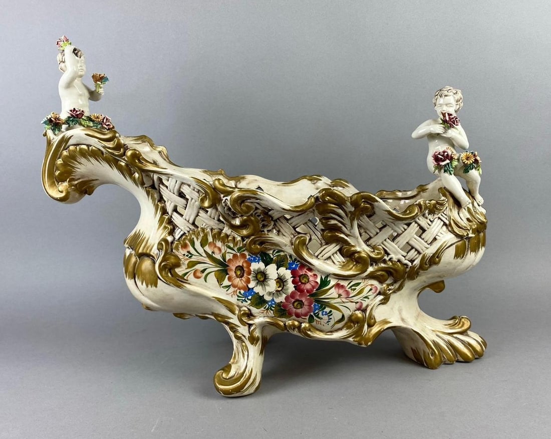 Antique Capodimonte Porcelain Centerpiece Basketweave Bowl: Italian Deoccia Bassano A/36/C. Measures H 16 x W 10 x L 22 inches. Cherub has repaired crack on wrist