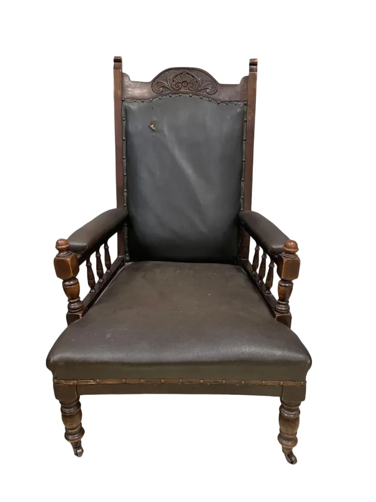 Antique Leather and Walnut Armchair: No in-house shipping available, 3rd party shipper or pickup. Spindle arms, carved headrest, hole on front and back in the leather, measures 42 1/4 inches x 27 inches x 31 inches