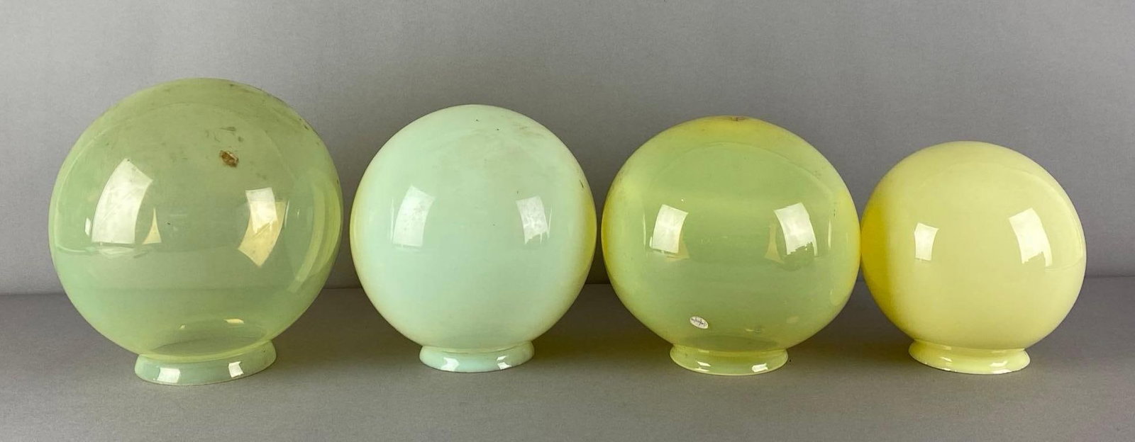 Group of 4 Vaseline Glass Globe Lamp Shades: need cleaning, largest measures 8 1/4 inches H x 7 1/4 inches W with a 4 inches fitter