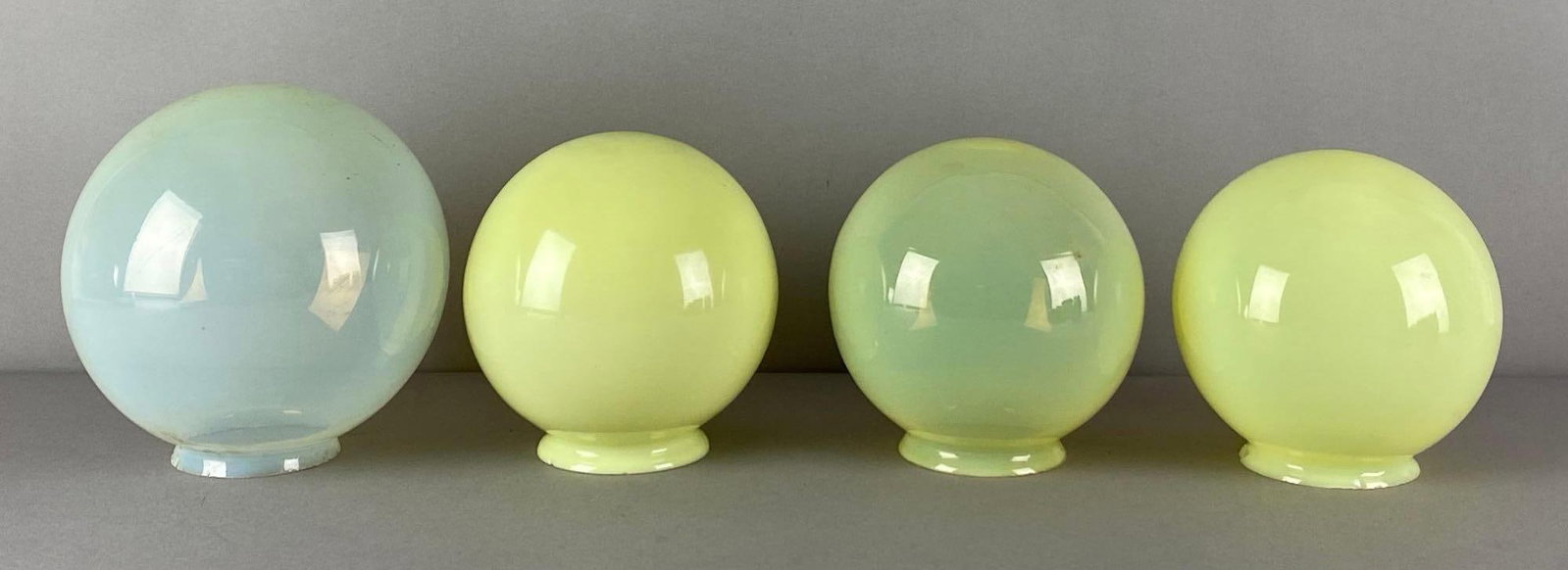 Group of 4 Vaseline Glass Globe Lamp Shades: Need cleaning, fleabites along fitters, largest measures 7 inches H x 6 1/2 inches W with a 3 inches Fitter