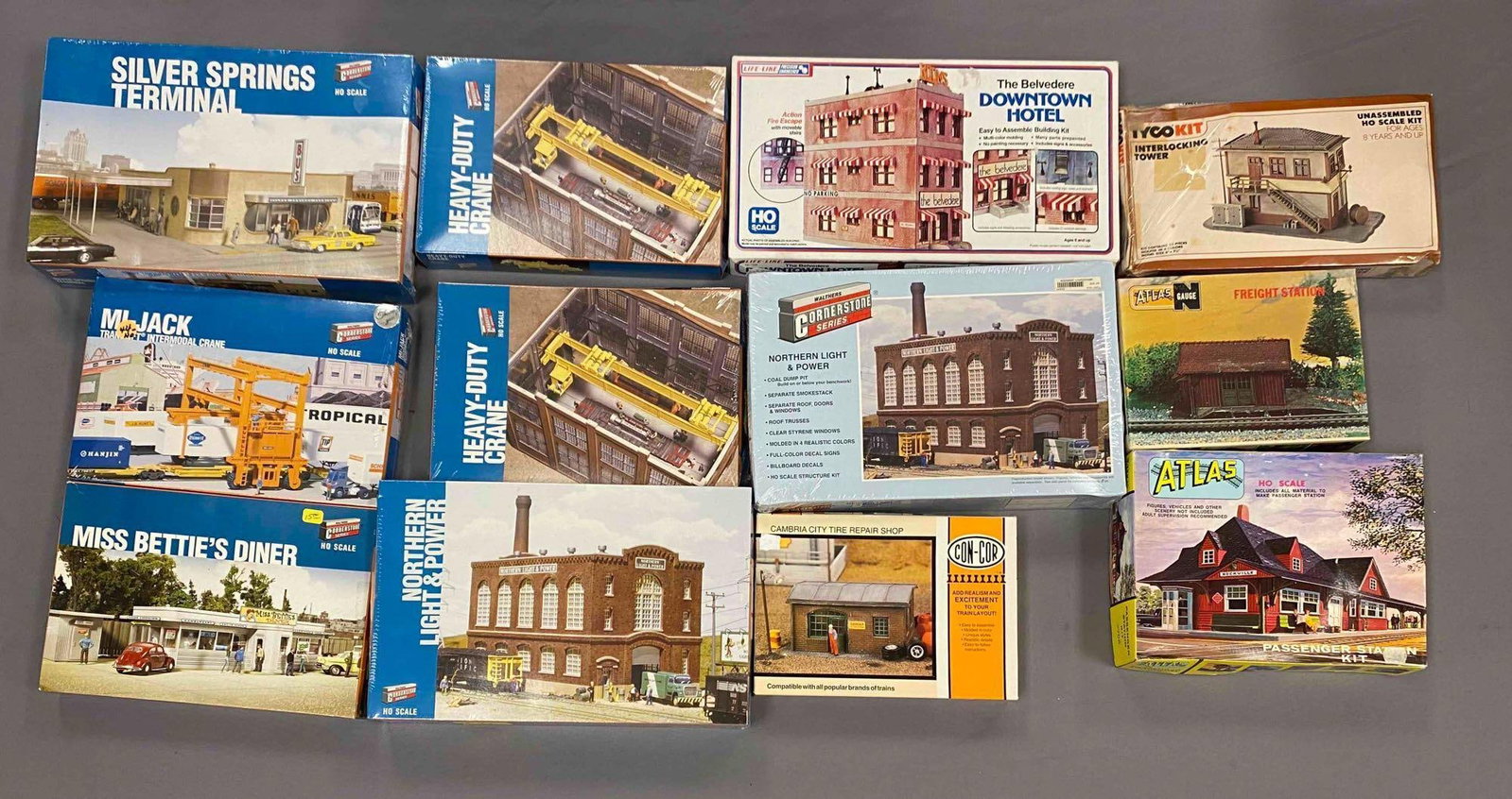 Group of Assorted HO Scale Model Train Building Plastic Model Kits: Most sealed, includes cambria city tire repair shop, freight station, downtown hotel and more, largest measures 9 inches H x 14 inches W