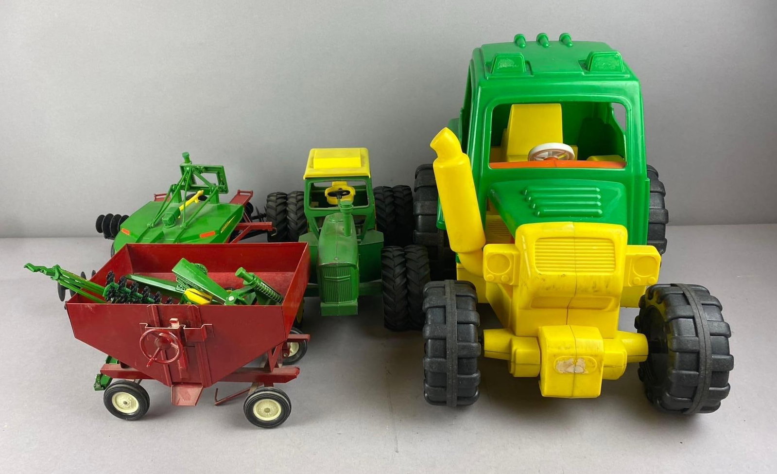 Group of Assorted John Deere 1/16 Scale Die-Cast Vehicles and More: Includes John Deere plastic toy, models, and more. Largest measures H 13 x W 12 x L 14 inches.