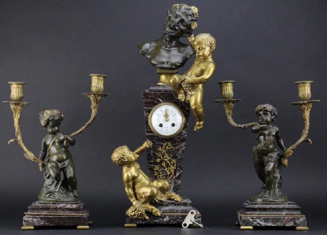 3 piece Clodion Figural Bronze Clock & Garniture Set: Antique French clock and garniture set signed Clodion, Michel Claude Clodion (1738-1814). Crafted of a deep red marble with powerful graining. Clock features gilt bronze cherub pulling the ear of Dion