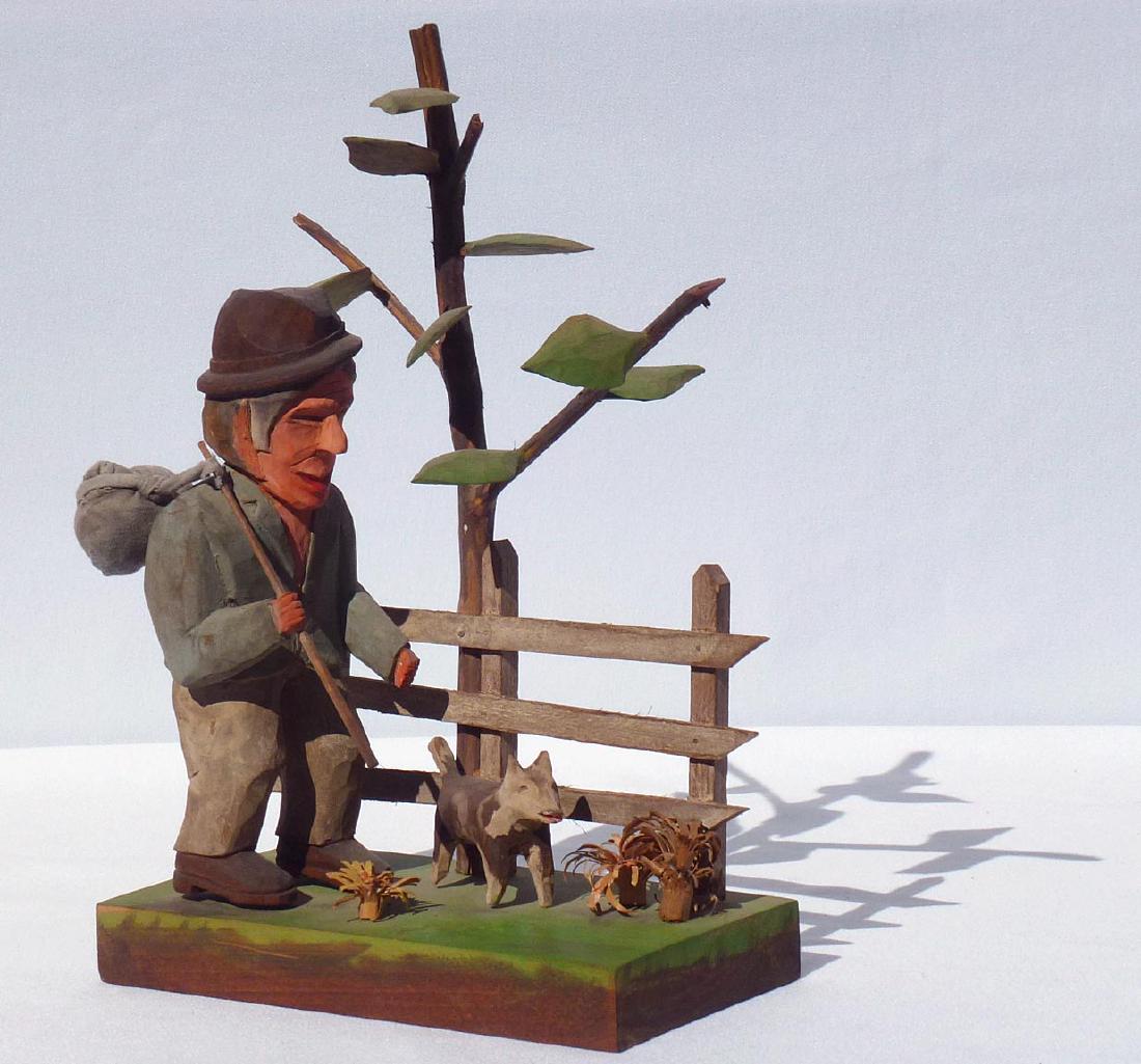 Unto Jarvi: man walking with a dog Outsider Folk Art: Carving by Unto Jarvi is a man walking with a dog. He is carrying a bundle over his shoulder like a hobo. The man and dog are next to a picket fence. A tree with individually carved leaves is on the o