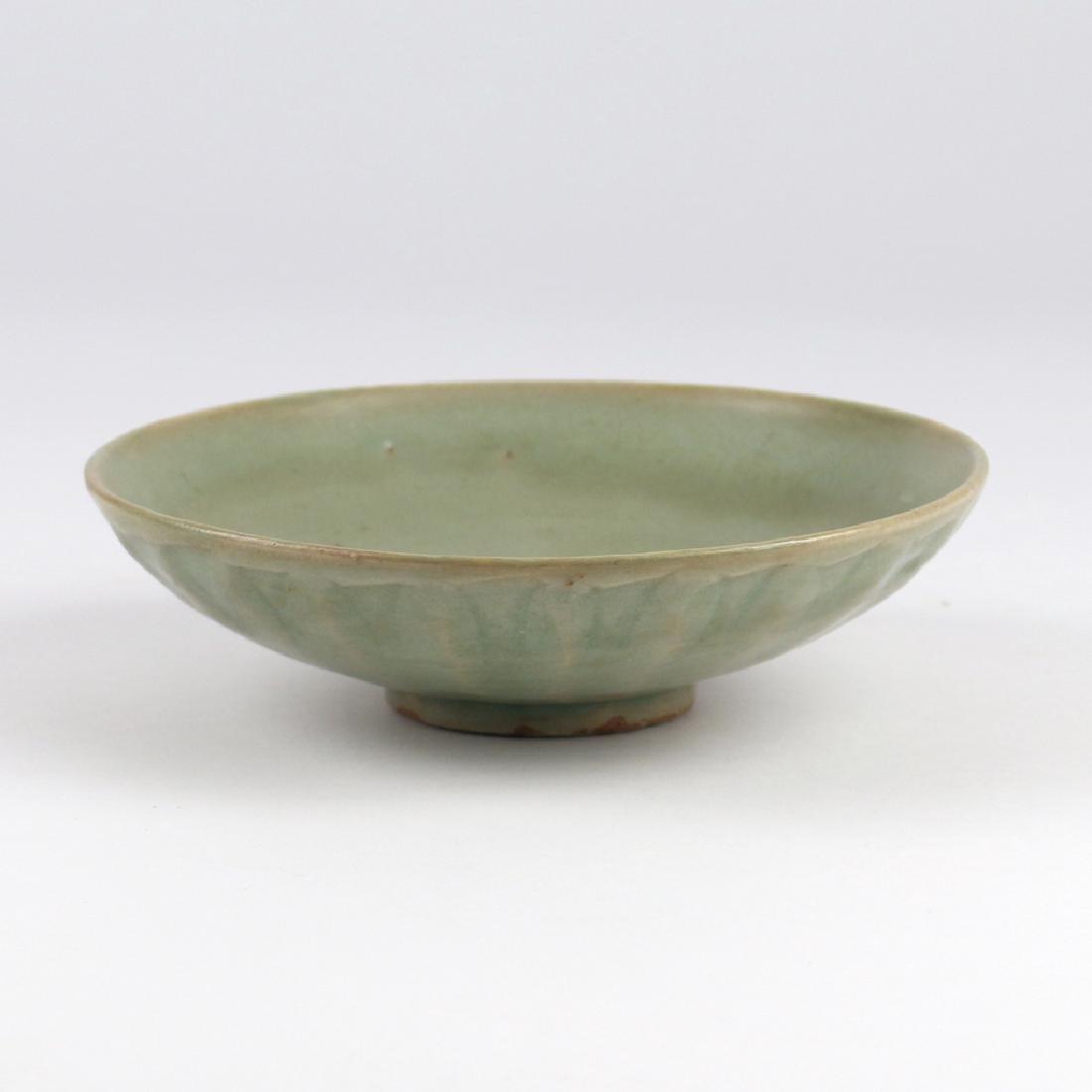 LONGQUAN CELADON CRYSANTHEMUM BOWL: China, Yuan to early Ming dynasty, with shallow, gently sloping sides having incised chrysanthemum pedals on the exterior and a small foot, the recessed and glazed base coming to a conical point, with
