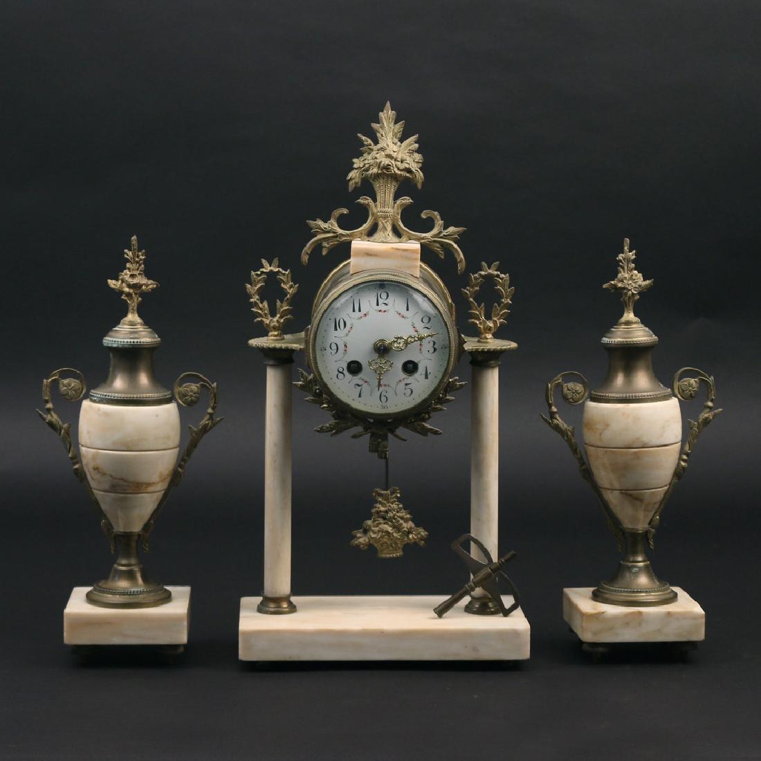 (3pc) FRENCH CLOCK GARNITURE: Comprised of a mantle clock and two urns, l.19th/e. 20th Century, marble with ormolu mounts, painted dial, the works signed "JS", back door marked "Made in France" h. 15-1/2" Provenance: Collection of