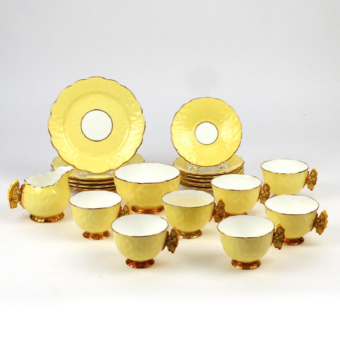 (22pc) AYNSLEY BONE CHINA TEA SET: with yellow ground and gilt edging, the tea cups with butterfly-form handles, green mark, comprising 7 cups; 7 saucers; 6 dessert plates; 1 creamer; and 1 open sugar w. 7 in. (plate) Condition: 1 cup