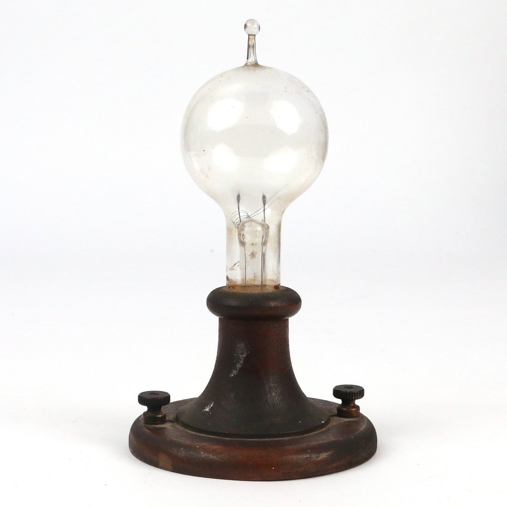 JULIUS BRAUNSDORF PROTOTYPE LIGHTBULB: An early blown glass filament type light bulb mounted in a wooden base with brass screws. Reputed to be made by Julius Braunsdorf, lighting pioneer involved in the creation of the Arc type light bulb 