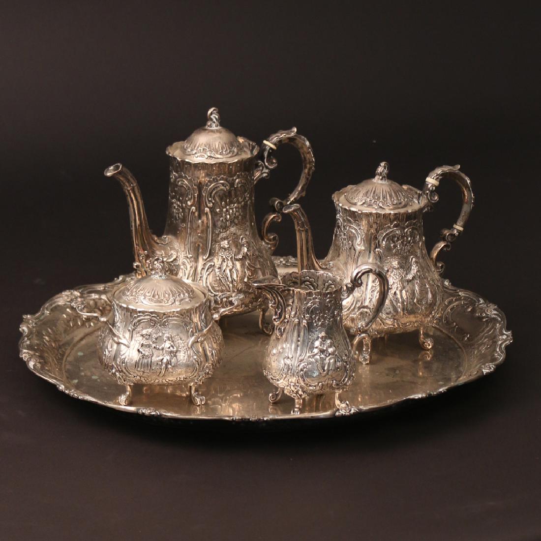 (5pc) '800' SILVER TEA & COFFEE SERVICE: including a four-piece service decorated in a rococo style with amorous couples, comprising a coffee pot, tea pot, covered sugar, and creamer; plus a similar oval serving tray, 19 x 17 in., 47 toz; al