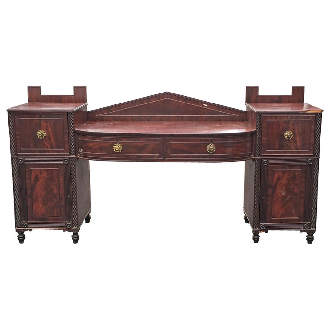 LATE REGENCY MAHOGANY SIDEBOARD: double pedestal having peaked backboard over bowed 2-drawer frieze, supported by pedestals w/bottle drw. and cabinet door opening to two drw., both over cabinet doors, rested on turned feet, h. 4 ft.,