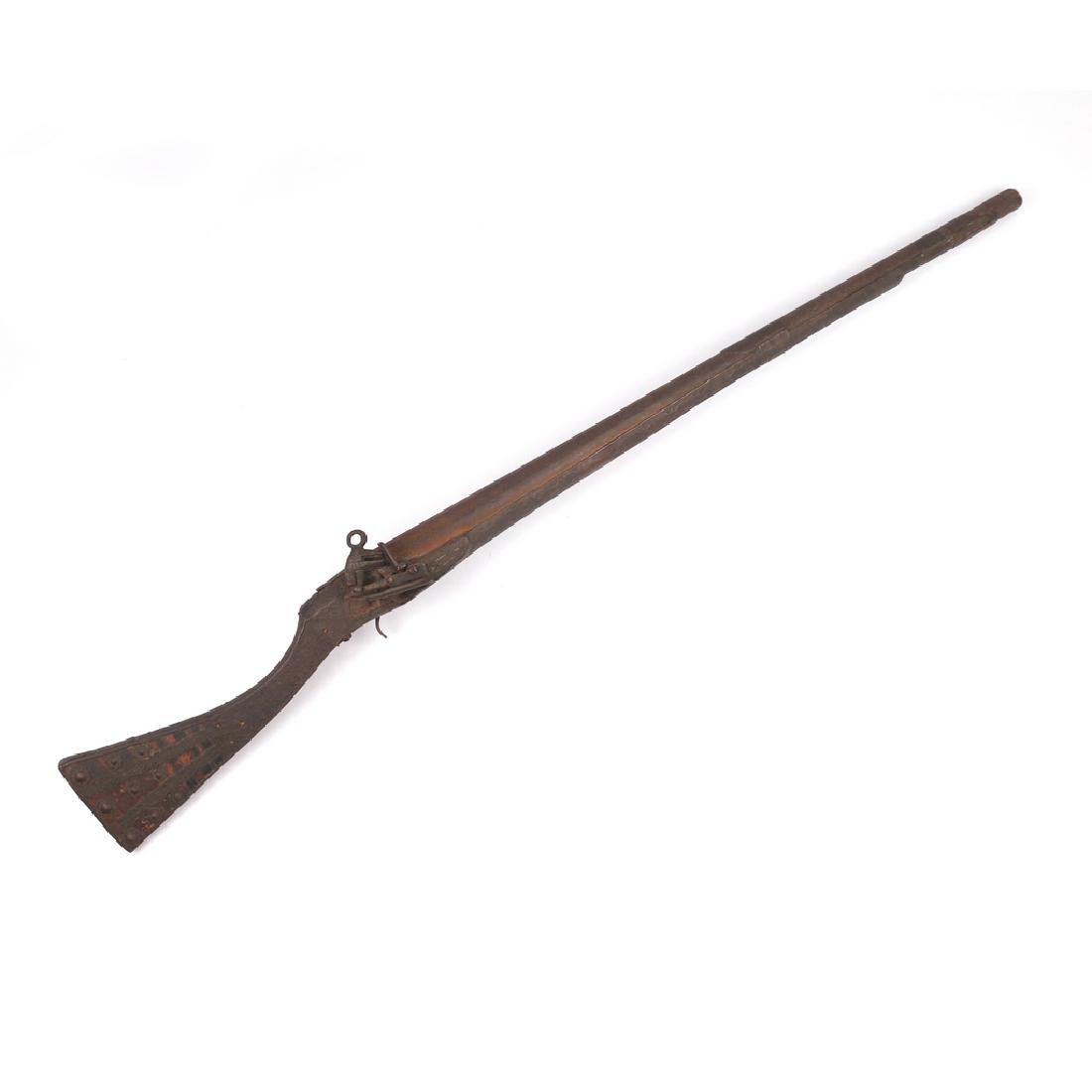 MIDDLE EASTERN RIFLE: An unusual short stock flintlock rifle with engraved 26in. barrel, banded wood stock, overall embossed applied decorations, saddle ring, length of pull 11in.; overall length 38 in.
