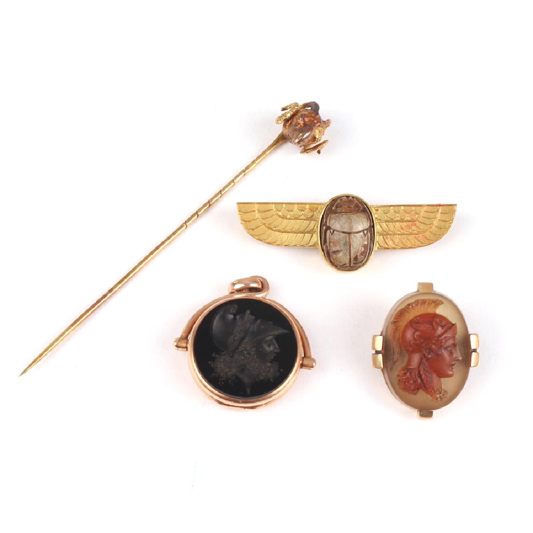 (4pc) FIGURAL GEMSTONE & GOLD JEWELRY: Including a carved scarab in a winged-form (tested to) 14k bar pin (l.1-3/4in., 7.0g), a bloodstone and carnelian intaglio locket fob with gold frame (dia. 1 in., 11.1g) a hardstone carved cameo pin w