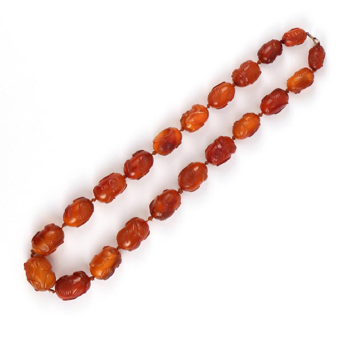 FORMED CARVED AMBER BEAD NECKLACE: Having twenty-one graduated oval beads with formed and carved nautilus, clam, and other seashells l.25-1/2 in., 124g; bead diameter range 12mm to 24mm