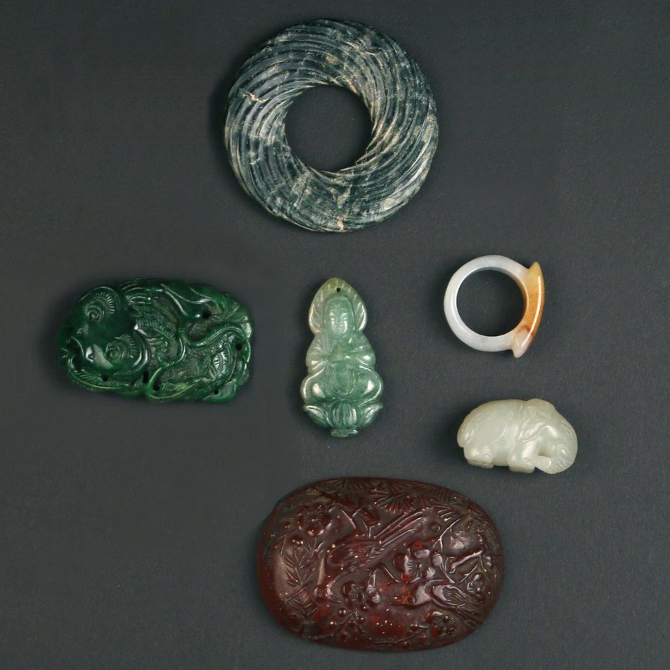 (6pc) MISC. CHINESE JADE & OTHER CARVINGS: including a carved amber oval pendant with birds among branches, having four small apertures for suspension; a mottled grey-green stone bi disc with spiral design; a spinach jade carving of a carp; an