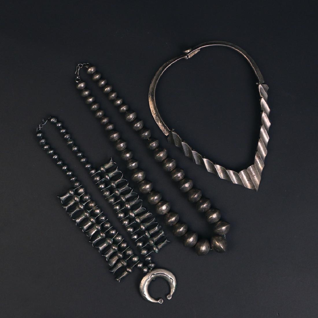 (3pc) STERLING SILVER NECKLACES: Including a Taxco articulated hard necklace (w. 4-3/8 x l.5-3/4in.), a necklace with graduated oblong engraved silver beads (l. 20 in.), and a sterling necklace with central pendant and hanging bell o
