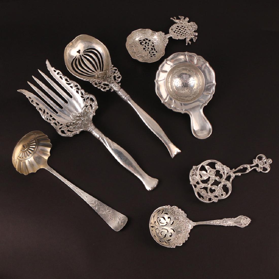 (7pc) STERLING SILVER ITEMS: Including a slotted spoon and similar reticulated serving fork, a Theodore B. Starr Rose patterned openwork spoon, a sterling pastry server, two tea strainers, and a J. Bach engraved ladle; total weig