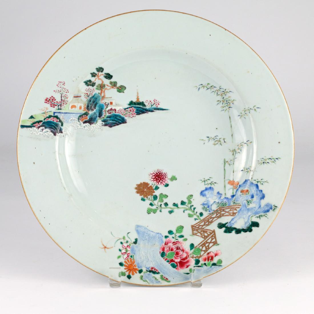 CHINESE EXPORT PORCELAIN CHARGER: late 18th Century, made for the Japanese market, with an island landscape at upper left and gated area of bamboo, flowers, and rocks at lower right delineated in famille rose enamels dia. 12-3/4 in.