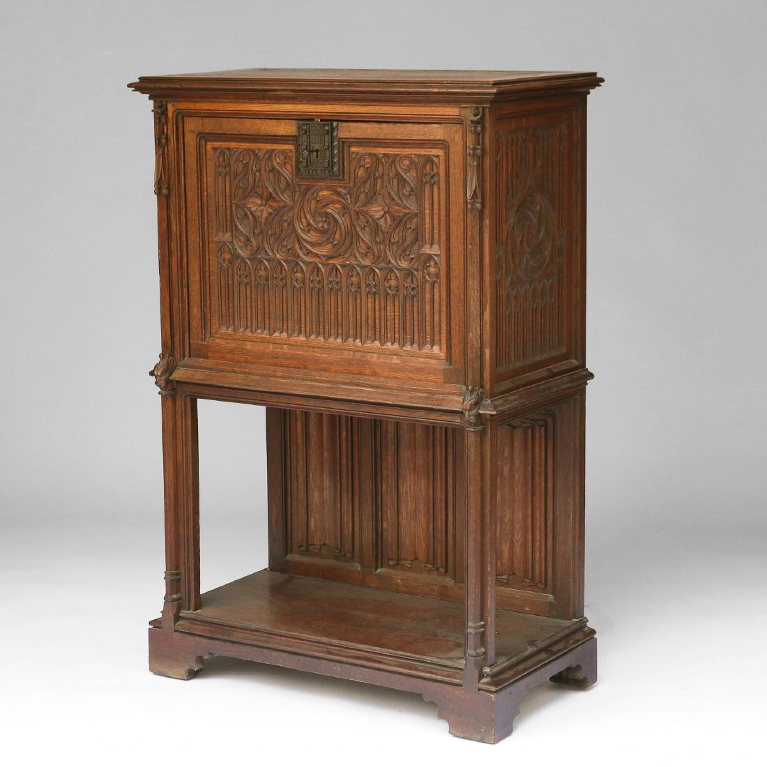GOTHIC REVIVAL OAK VARGUENO: 19th Century, with fall-front revealing original leather writing surface and five pigeon-hole shelves over three short drawers, the exterior with elaborate gothic fretwork and linen-fold carving to lo