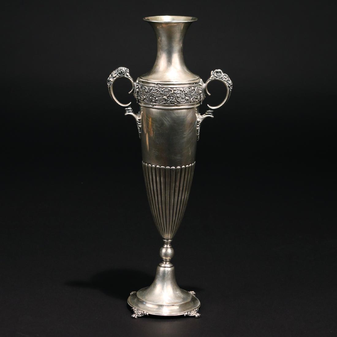 TIFFANY STERLING SILVER BUD VASE: circa 1891-1902, of amphora form with classical band at the shoulder, double handles, gadrooned belly and circular base raised by four paw feet, 12 ozt h. 12 in. Condition: lip slightly bent on one si