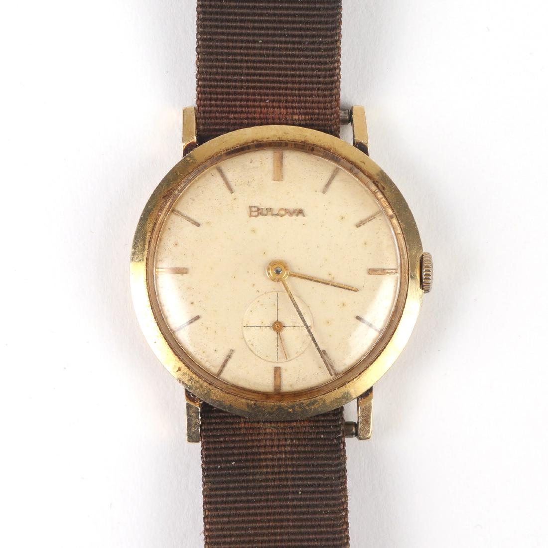 BULOVA 14k GOLD WRISTWATCH: off-white dial with gold baton numerals (some spotting) sub seconds dial, manual wind, in a 14k yellow gold case on a canvas strap; caseback marked "14k gold / Bulova LB / D259614"; case diameter 34mm
