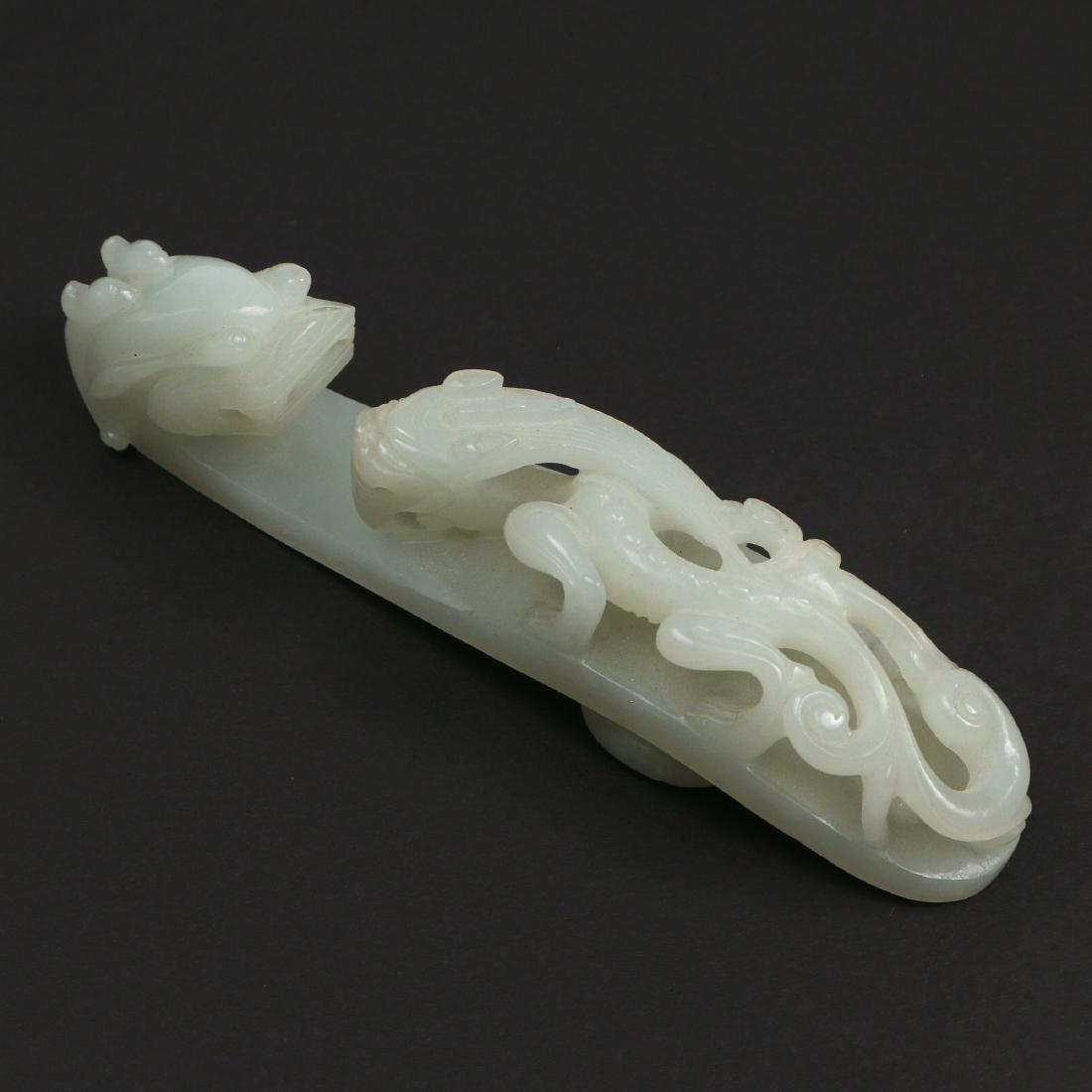 CHINESE IMPERIAL MUTTON FAT JADE BELT HOOK: Qianlong period (c. 1736-1795), of typical dragonet design with carved and undercut chilong crawling towards a dragon-head terminal, the reverse with a knob carved as a flower head, the stone of an ev