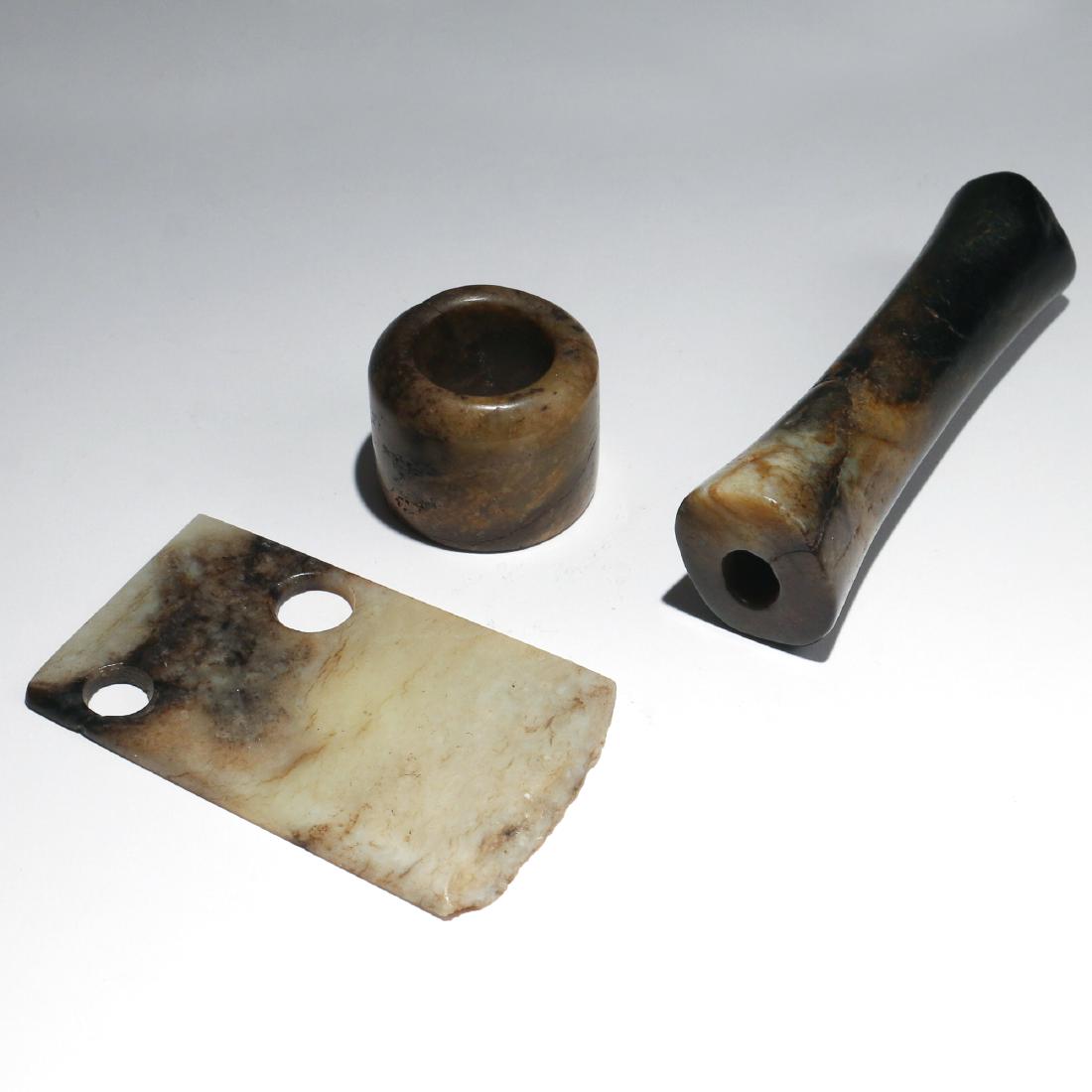 (3pc) CHINESE SHANG DYNASTY JADE CARVINGS: Shang dynasty (c. 1600-1046 BCE), including a nephrite blade of light to dark grey-green, a mottled greenish-brown archer's ring, and a long cylindrical pendant bead in mottled dark green nephrite fad