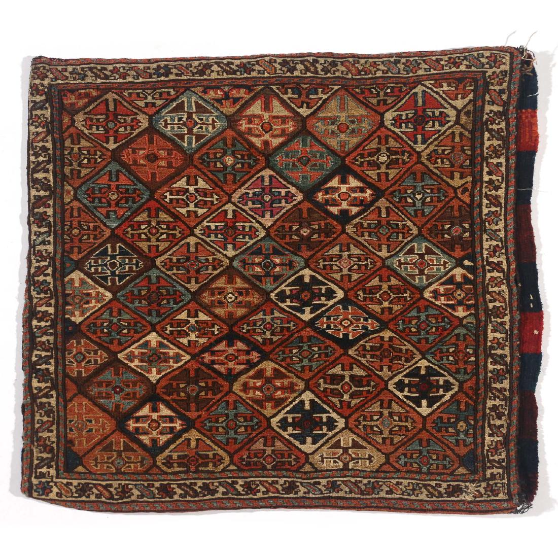 SHAHSAVAN SOUMAC SADDLE BAG: early 20th Century, having a lattice design of shield-like guls in a multitude of colors enclosed by an ivory-colored meander border, the reverse with flatwoven bands in various shades of red and blue