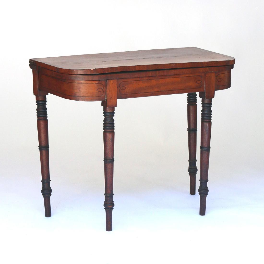 REGENCY INLAID MAHOGANY FLIP-TOP GAME TABLE: early 19th Century, with cross-banded mahogany top bowed at the corners revealing a green-felt game surface, over a string-inlaid frieze and ring-turned legs ending in peg feet h. 30 w. 36 d. 17-1/2 i