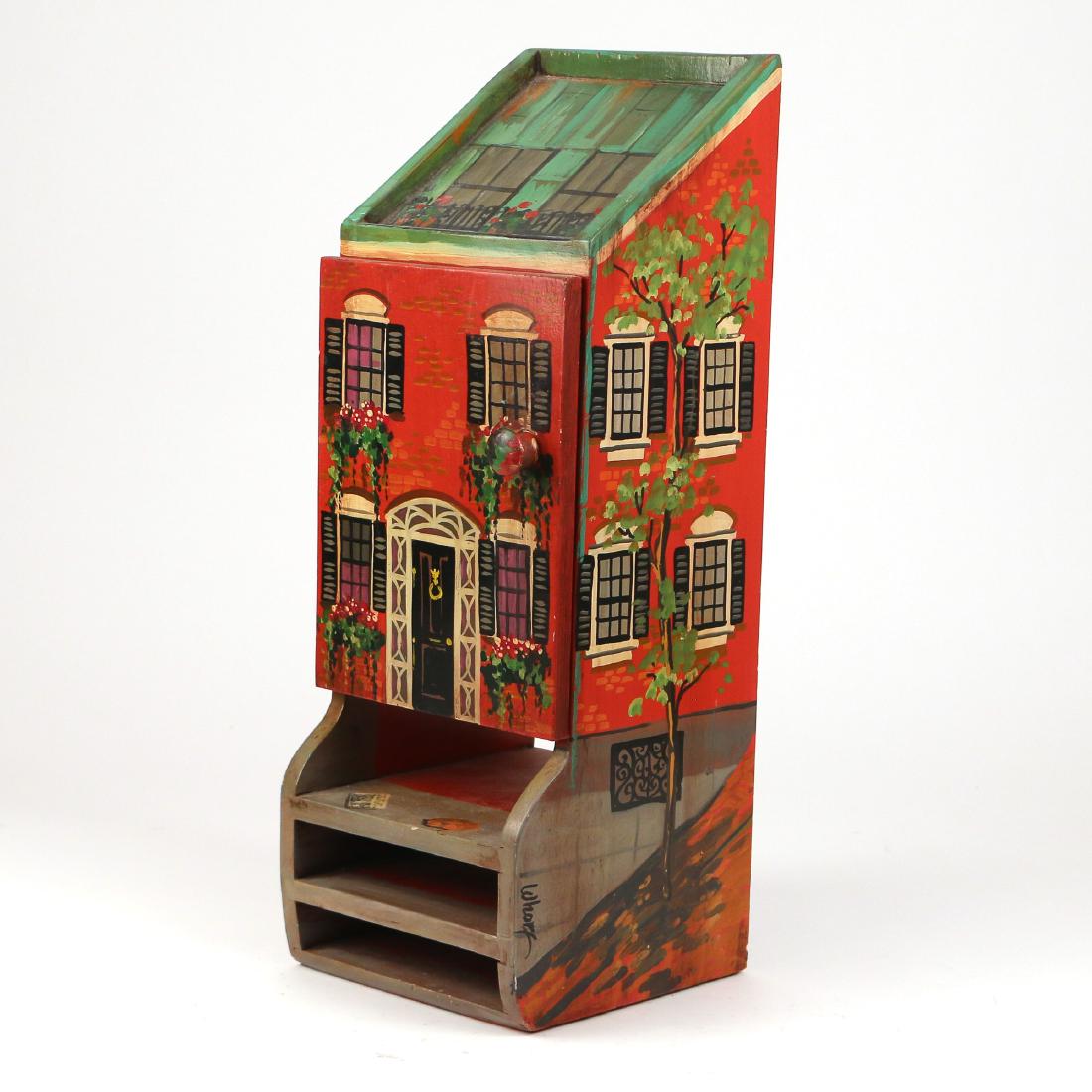20TH C. FOLK ART PAINTED HANGING LETTER BOX: Painted by Nancy Whorf, daughter of noted American artist John Whorf; in the form of a red brick row house with green roof, decorated with trees and flowers, having lower shelves and a single door h.