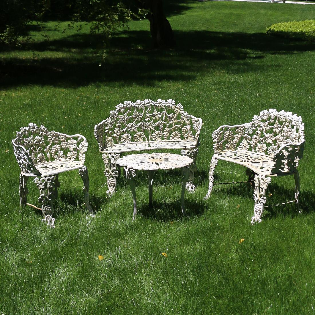 (4pc) WROUGHT-IRON GARDEN FURNITURE: Â‘Grape-leafÂ’ pattern, comprising two settees, a chair, and a round side table h. 28 w. 33 d. 22 in. (settee) [IN SITU] Preview for this item is by appointment only, it is not on display in our