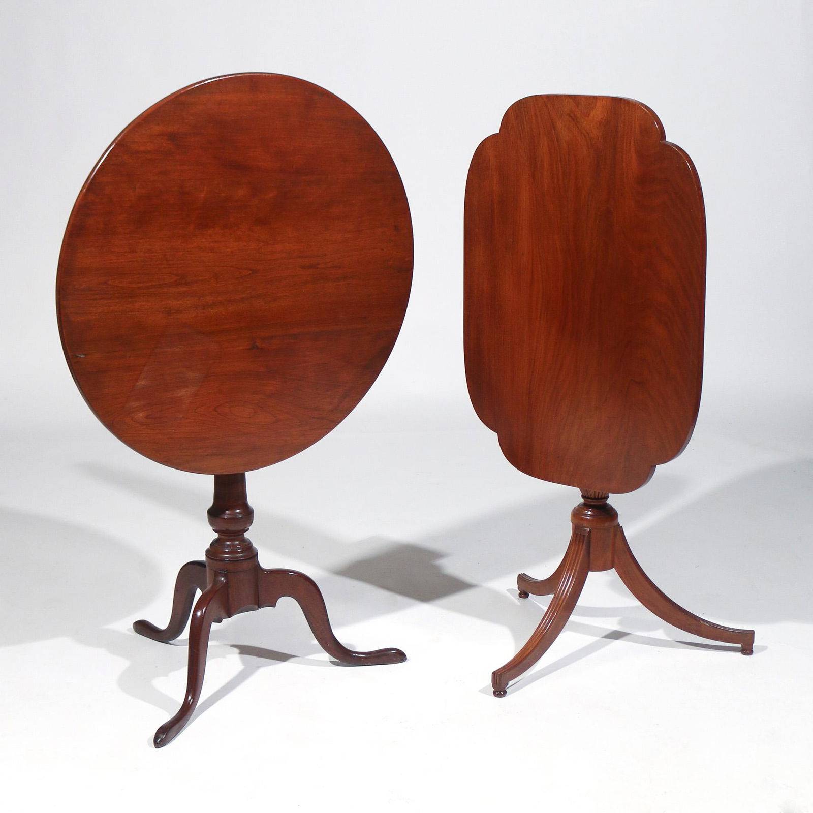 (2pc) ANTIQUE TILT-TOP TEA TABLES: 19th Century, American and/or English, both with tripod bases, including one in mahogany with a clover-shaped top over a reeded urn and legs, h. 27 w. 28 d. 20 in.; and one in stained cherry with a ci