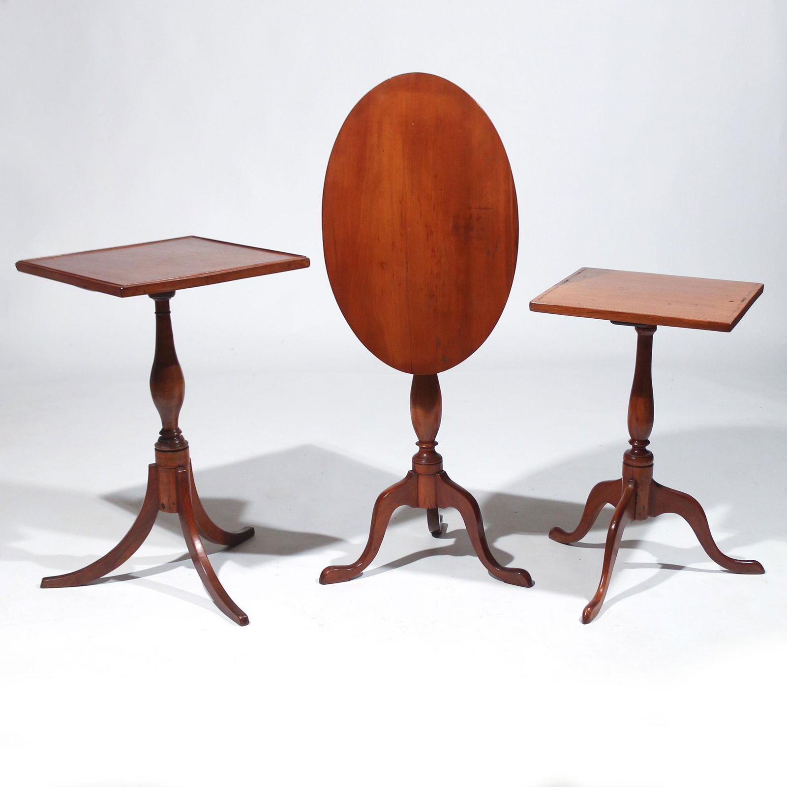 (3pc) ANTIQUE AMERICAN CHERRY TEA TABLES: 19th Century, all with tripod bases, including one with a square top with line molding; one with a square top with barber-pole inlay; and one with an oval tilt-top h. 28 in. (tallest) Provenance: Mrs.
