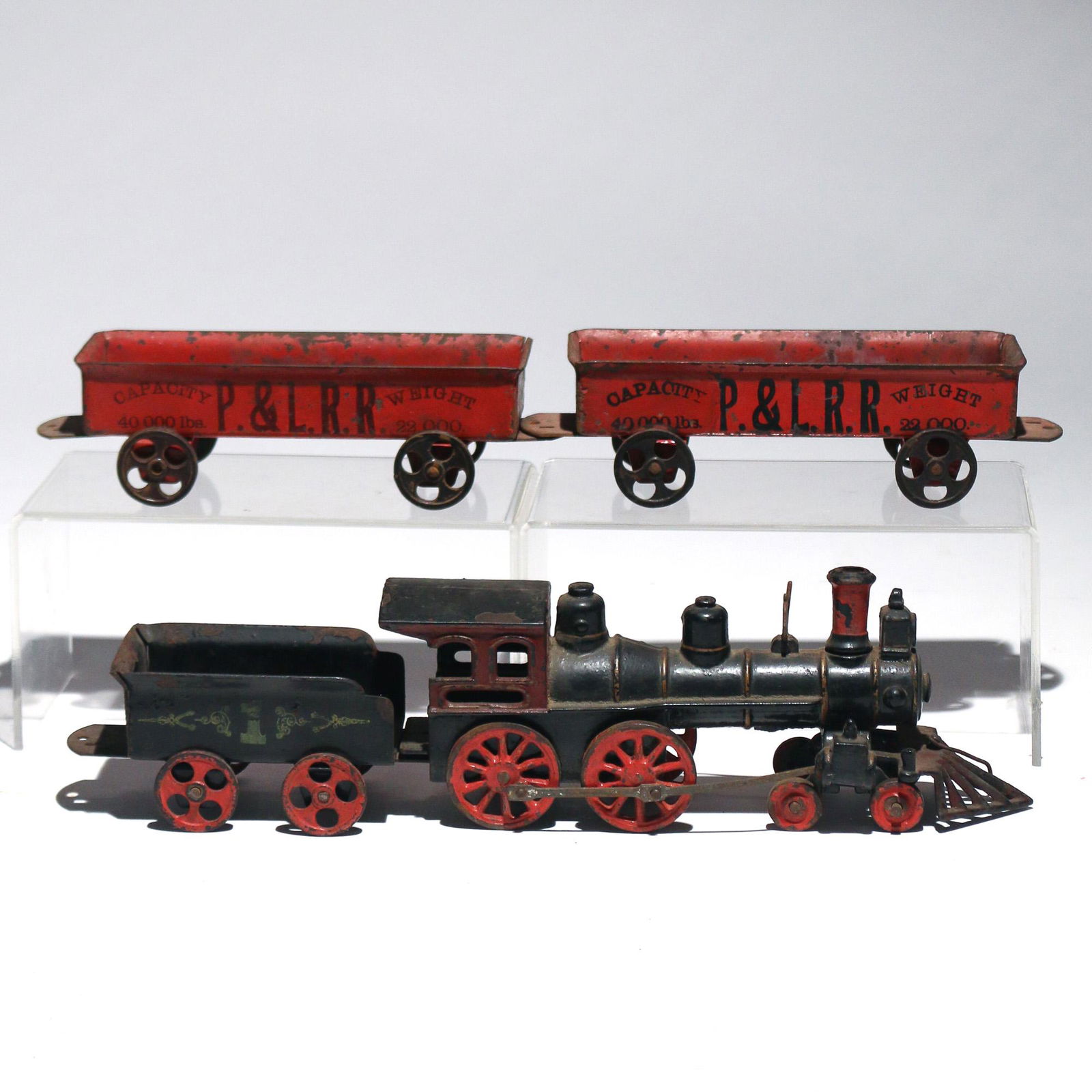 (4pc) EARLY PAINTED METAL TOY TRAIN: Including a cast iron black painted engine with red wheels and stack, a coal car with red wheels, and two red painted 'P. & L.R.R.' open freight cars (2-3/8 x 8-3/4 x 2-1/2 in., ea.) h. 3-1/2 w. 10 d.