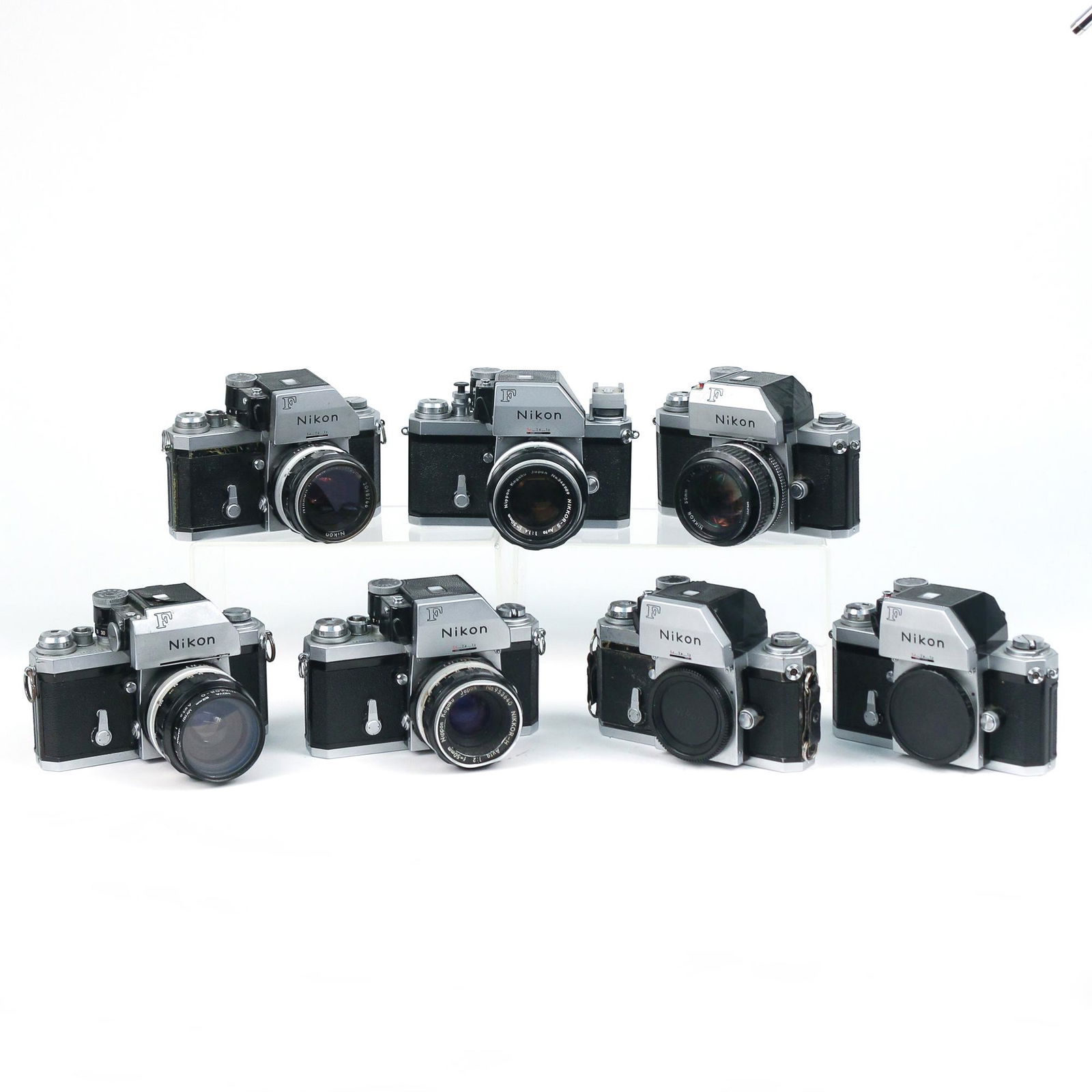 (7pc) NIKON F CHROME FILM CAMERAS: including a Nikon F with a Nikkor-O 35mm lens, a Nikon F with a Nikkor-H 50mm lens [dents], a Nikon F with a Nikkor 50mm lens, a Nikon F with a Nikkor-H 50mm lens, two Nikon F cameras with no lens, an