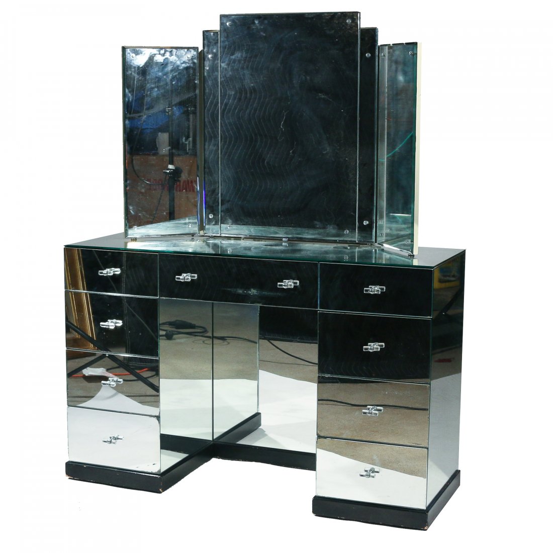 A. MARCHAND INC. MIRRORED VANITY: early 20th century, kneehole vanity desk with mirror; solid mahogany with applied mirrored top, sides, and drawer fronts, with lucite pulls; tri-fold beveled mirror with slide actuated rotating hidden