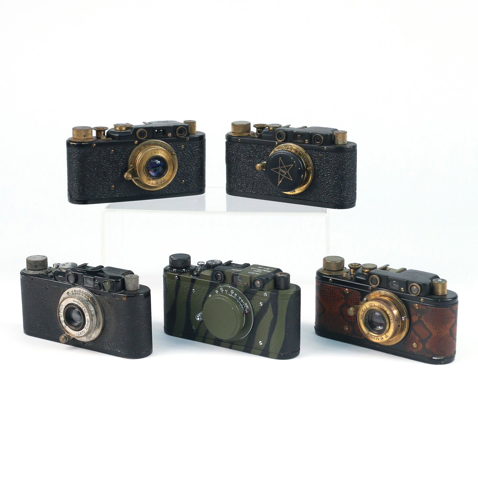 (5pc) BLACK REPLICA LEICA CAMERAS: including a Black camera with snakeskin grip; a black camera with black grip; plus two black cameras with black grips and Cyrillic names; plus a Cyrillic camera with camouflage scheme