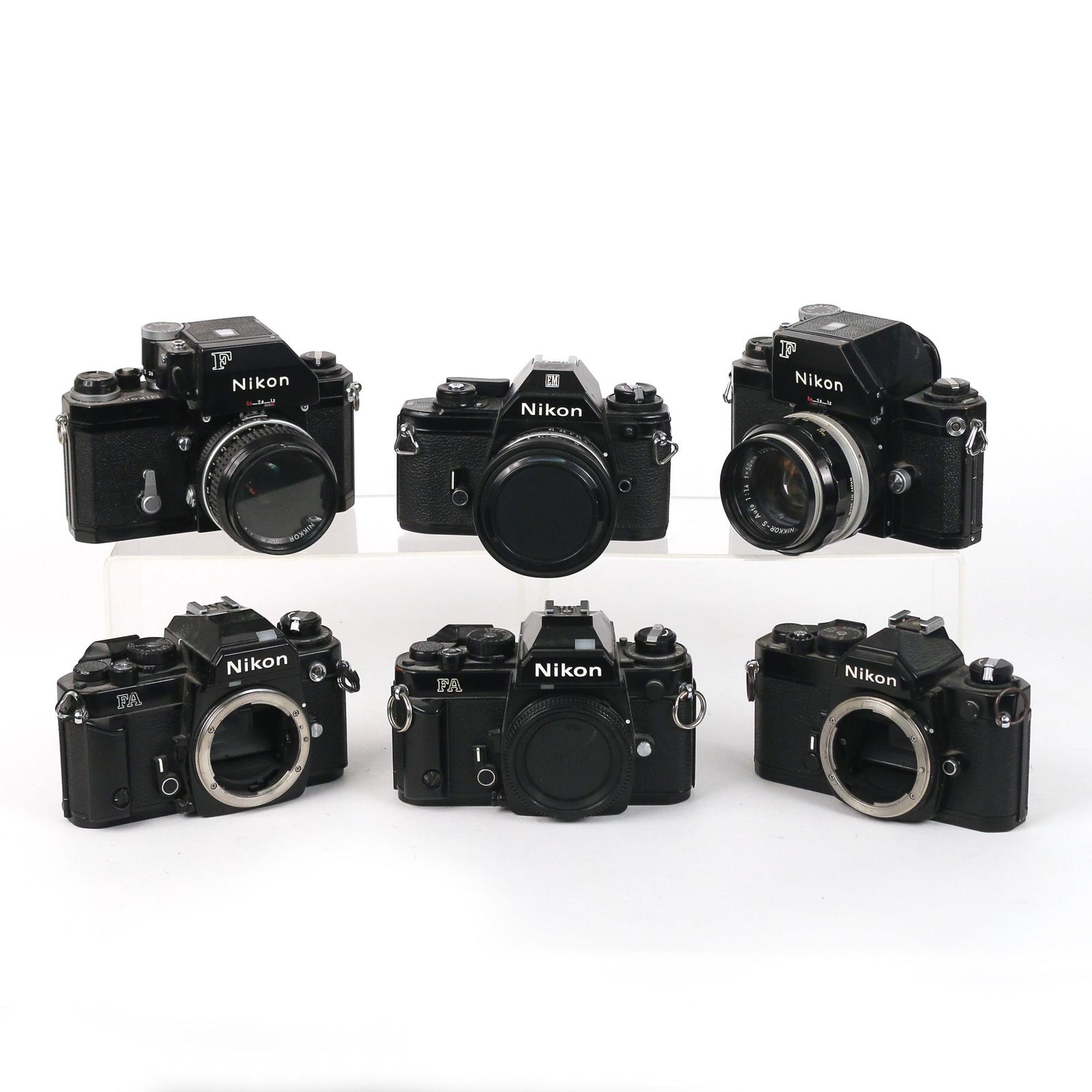 (6pc) BLACK NIKON FILM CAMERAS: including two Nikon F cameras [one with dent to pentaprism], each with a Nikkor 50mm lens; two Nikon FA cameras, both without lenses; a Nikon FM camera (No. 2558179) without lens; and a Nikon EM camer