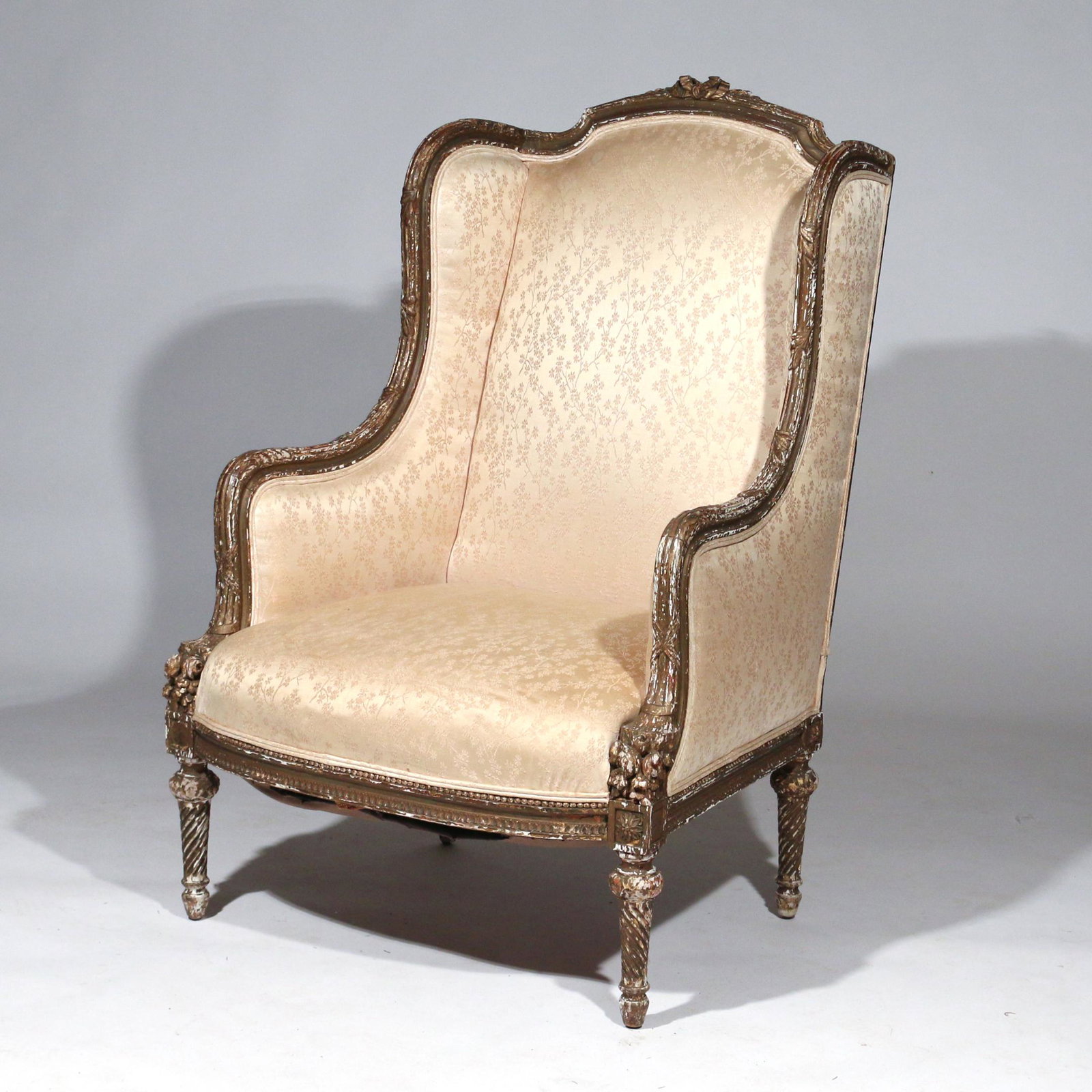 LOUIS XVI BERGERE A OREILLES CHAIR: 18th century or later, carved and gilt wood, crested by a French bow with channeling, terminating in a cornucopia; spiral turned legs h. 42 w. 29 d. 31 in. Provenance: from the estate of an important 