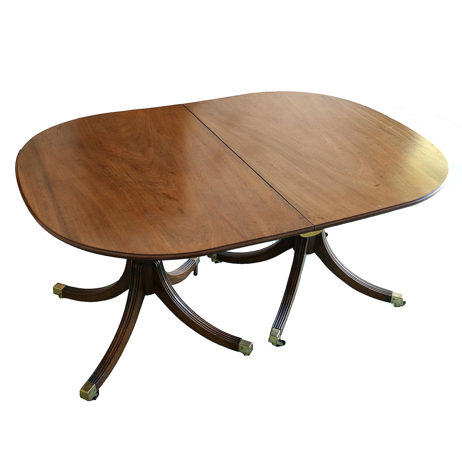 SHERATON DOUBLE PEDESTAL DINING TABLE: table supported by two carved pedestals each with four Duncan Phyfe style splay legs having brass caps and casters; including two leaves (w. 18-3/4 in. each) h. 28-1/2 w. 57 d. 42 in. (without leaves)