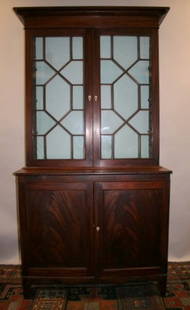 GEO III MAHOGANY BOOKCASE CABINET: CA. 1830, HAVING STEPBACK DBL. GLAZED DOORS W/MUNTINS & BONE ESCUTCHEONS OVER DBL. CABINET DOORS, FR. SPLAYED FEET, COND.: 3-GLASS PANELS W/CRACKS, H. 87, W. 44", D. 21", 2 PC. CONSTRUCTION