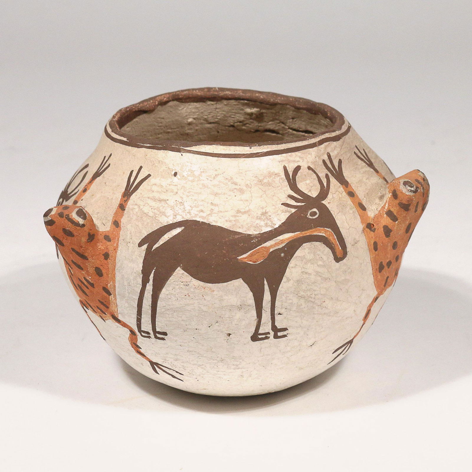 EARLY ZUNI PUEBLO POLYCHROME OLLA: 19th/early 20th century, with three frog fetish handles alternating with painted deer, all on a white ground h. 4-1/4 dia. 6 in. Provenance:Private Collection, Waccabuc, NY