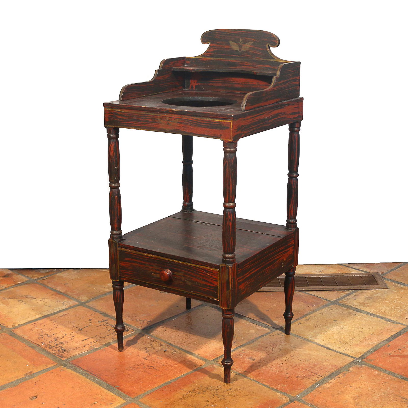19TH C. AMERICAN GRAIN PAINTED WASH STAND: , black and red grain painted with gold stenciled eagles and embellishments, open wash basin on turned supports over a lower shelf with single drawer h. 36 w. 16 d. 16 in. Provenance:the estate of a S