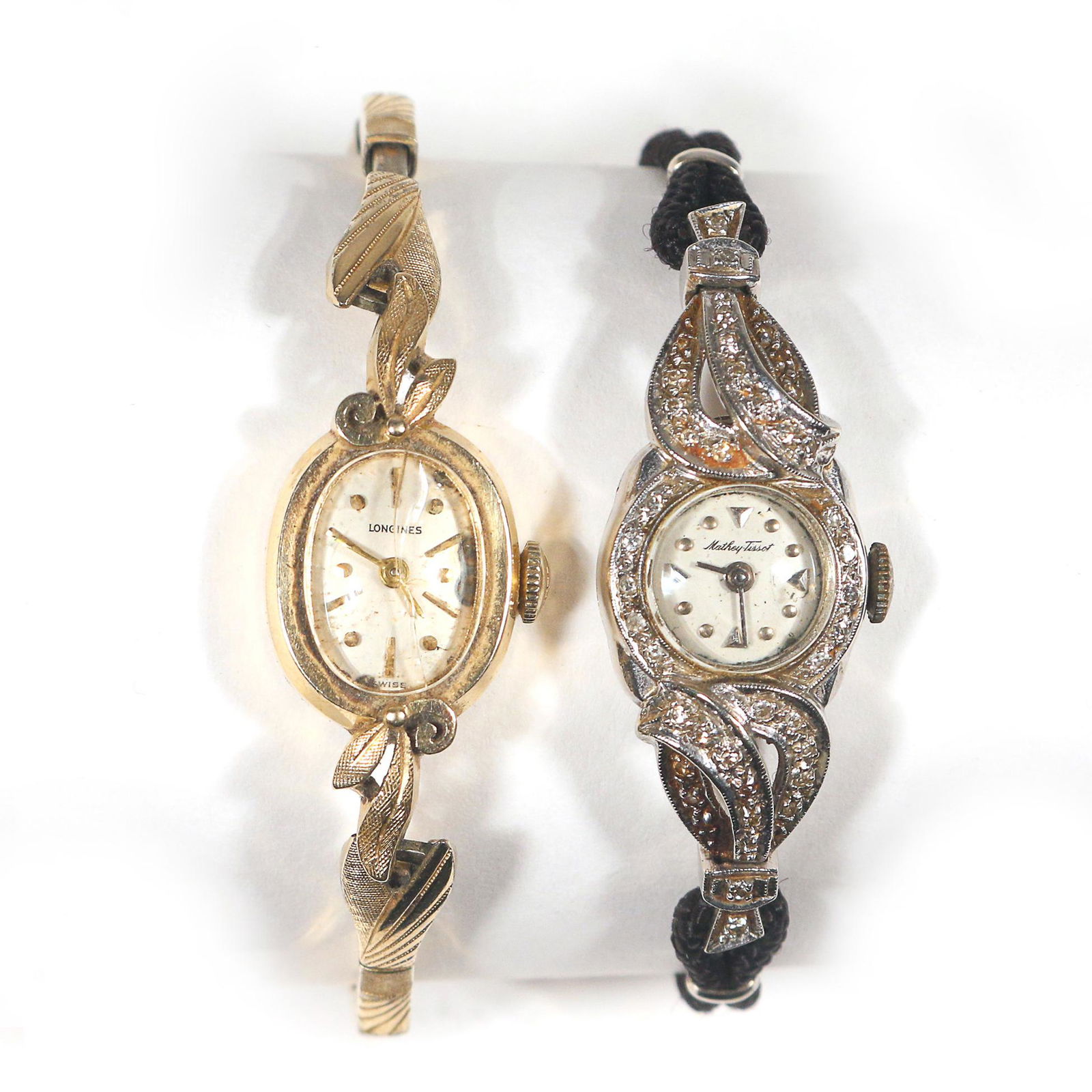 (2pc) 14k GOLD LADY'S WATCHES: including a Longines wristwatch on adjustable gold band [cracked glass/crystal]; and a Mathey Tissot watch adorned with diamonds on a black woven band; both cases marked 14k on the back; together 25.3