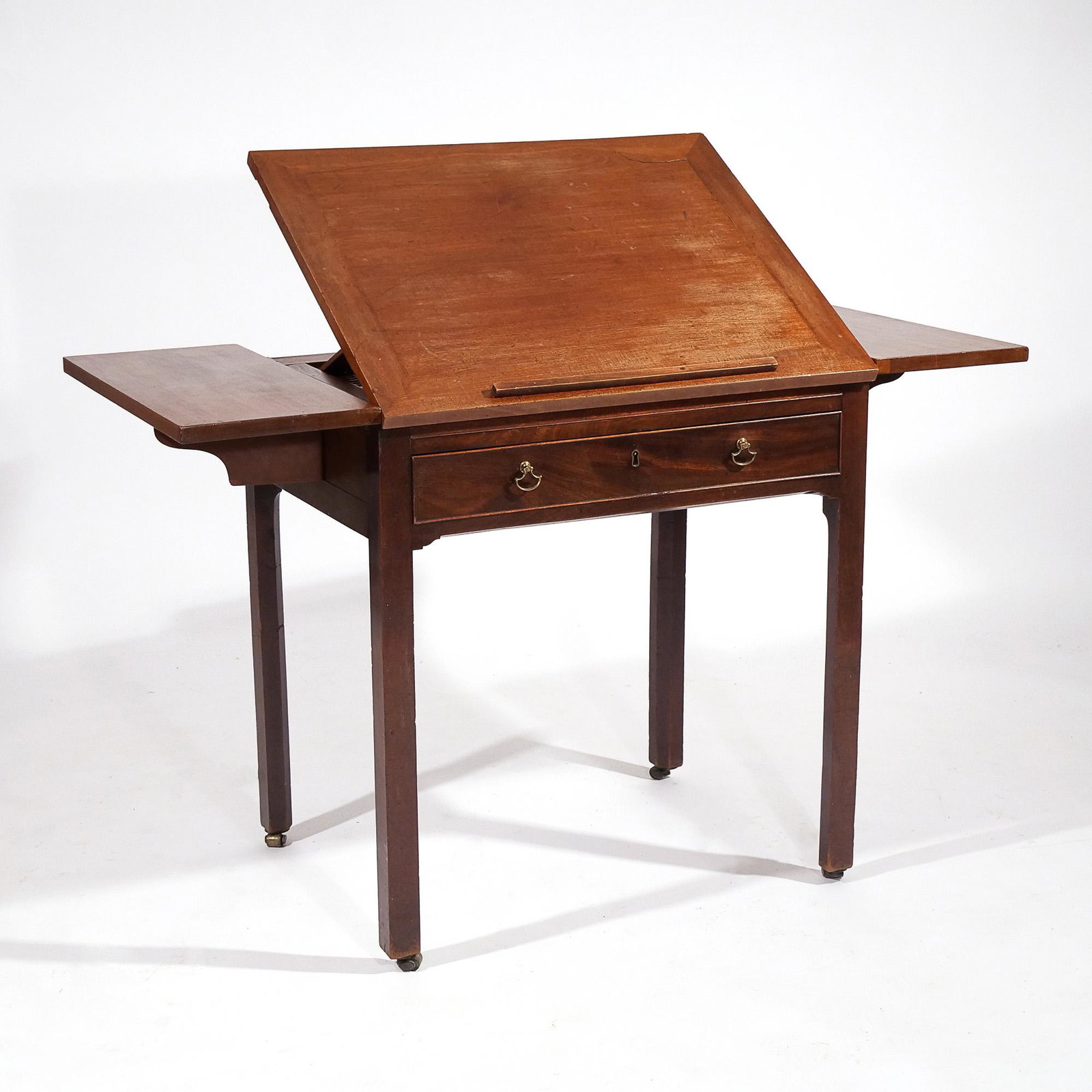 19th CENTURY ENGLISH ARCHITECT'S DESK: Having a ratcheted top flanked by drop sides, over full-width drawer, on square legs terminating in casters h. 29-1/2 w. 29-1/2 d. 22 in. Provenance: Descended through a Bedford, NY estate [In Situ It