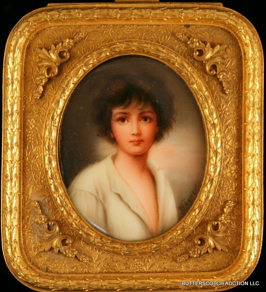 OVAL PORCELAIN PLAQUE OF A YOUNG BOY: sgd. "Wagner," set into a rectangular ormolu box. Verso marked with "Peppo" in red ink and an incised "22"; Plaque: 2 ½" x 2"; the box: 3 ¾ x 3 ¼ x 1 ¼"