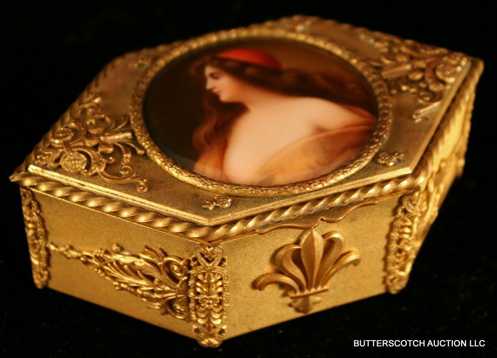 ROUND PORCELAIN PLAQUE "UNA GITANA": sgd. "Wagner", after Angelo Asti, set into an hexagonal ormolu box; verso incised with "451" and an "MR" mark; the plaque D: 2 ½"; the box: 5" x 3" x 1 ½"